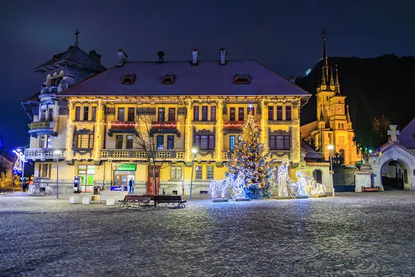 Bir binanın önünde bir Noel ağacı parlıyor. Sahne, binanın önündeki bankların ve bankların olduğu bir avluda geçiyor. 13 Aralık 2024 Brasov Romanya