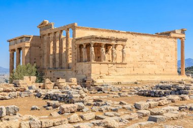 Sütunları ve avlusu olan büyük bir bina. Bina eski ve bir sürü taşı var. Avlu boş ve gökyüzü mavi, Atina 'da Akropolis