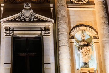 Klasik taş heykel geceleyin tarihi bina cephesinde aydınlandı.