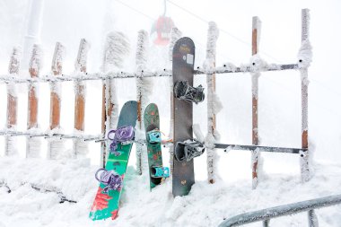 Buzlu bir çitin üzerinde renkli snowboardlar olan karlı bir dağ manzarası. 15 Aralık 2024 'te Romanya.