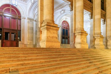 Geceleyin heybetli sütunları olan tarihi binanın büyük girişi. 8 Mart 2025 Bükreş Romanya.