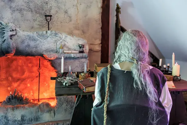 Uzun saçlı bir adam önünde mumla bir masada oturur. 16 Aralık 2024 Bran Romanya.