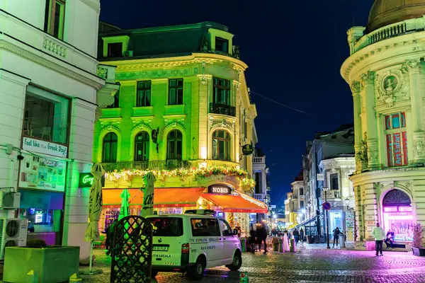 Parlak neon ışıkları olan tarihi Avrupa caddesinde hayat dolu bir gece hayatı. 8 Mart 2025 Bükreş Romanya.
