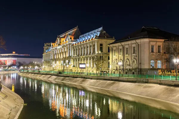 Gece kanalı sahnesinde aydınlatılmış mimariyle yansıyan tarihi binalar. 8 Mart 2025 Bükreş Romanya.