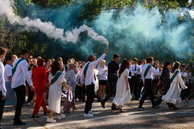 Mezuniyet töreninde mavi dumanlı bir grup genç. 31 Mayıs 2024 Balti Moldova.