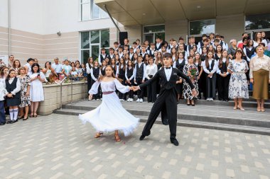 Genç beyaz dansçılar açık hava töreninde okul seyircilerinin önünde gösteri yapıyorlar. 2 Eylül 2024 Balti Moldova.