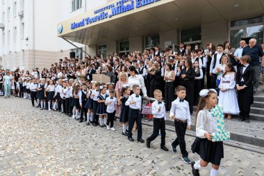 Okul törenindeki çocuklar ve yetişkinler açık havada resmi kıyafetlerle. 2 Eylül 2024 Balti Moldova.