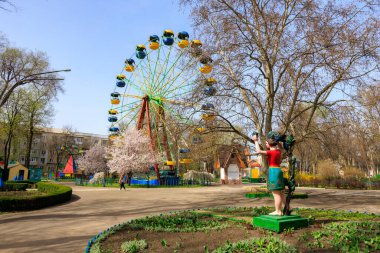 Atlıkarıncalı bir park ve bir kadın heykeli. Park boş ve heykel de parkın ortasında. 1 Nisan 2024 Balti Moldova