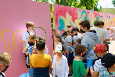Gençlik yaratıcılığı: işbirlikçi açık hava grafiti sanat projesine katılan çocuklar. 31 Mayıs 2024 Balti Moldova.