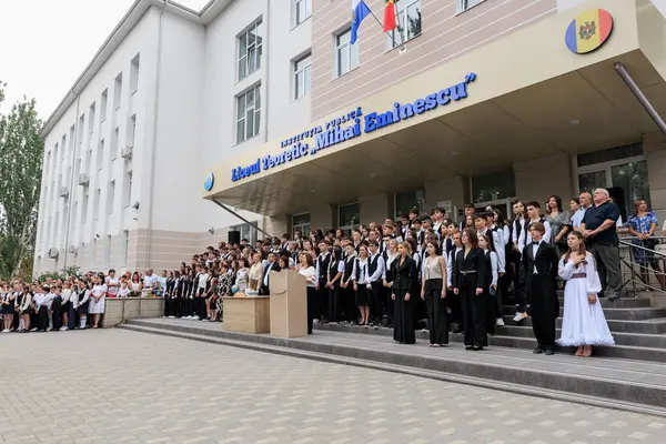 Çeşitli kalabalık ve mezunlarla Avrupa binasının dışında lise mezuniyet töreni. 2 Eylül 2024 Balti Moldova.