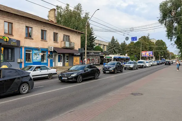 Bulutlu bir günde trafik ve mağazaların olduğu şehir caddesi manzarası. 11 Eylül 2024 Balti Moldova.