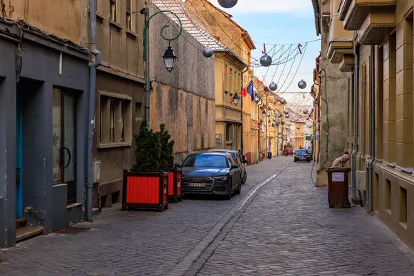 Yan tarafında bir araba park edilmiş dar bir cadde. Cadde binalarla kaplı ve kaldırım taşı yüzeyi var. 14 Aralık 2024 Brasov Romanya