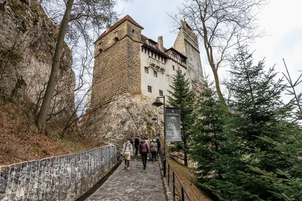 Bir grup insan bir şatonun önünde taş bir yolda yürüyor. 16 Aralık 2024 Bran Romanya.
