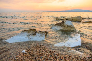 Okyanus sakin ve gökyüzü güzel turuncu bir renktir. Sudaki kayalar beyaz ve sahilde bazı küçük kayalar var.