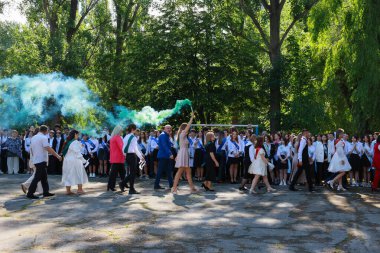 Farklı lise öğrencileri ve açık havada renkli dumanlarla yapılan bir kutlama. 31 Mayıs 2024 Balti Moldova.