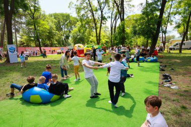 Çocuklar parktaki açık hava etkinliklerinde aileleri ve oyunlarıyla yeşil çimlerde oynuyorlar. 31 Mayıs 2024 Balti Moldova.