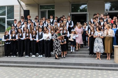 Bir grup Kafkas genci ve yetişkin resmi giysiler içinde okul merdivenlerinde toplandı. 2 Eylül 2024 Balti Moldova.