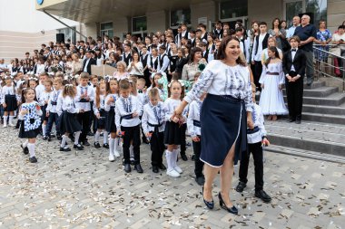 Okul kutlamalarında geleneksel giyinmiş beyaz çocuklar ve yetişkinler. 2 Eylül 2024 Balti Moldova.