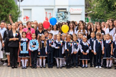 Okul töreninde çocuklar ve üniformalı yetişkinler balon tutuyordu. 2 Eylül 2024 Balti Moldova.