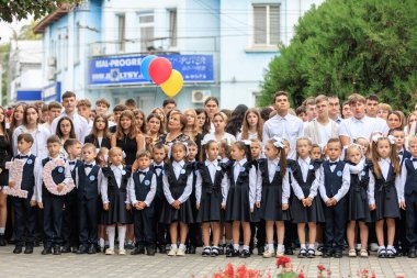 Okul çocukları ve yetişkinler tören için dışarıda toplandılar. 2 Eylül 2024 Balti Moldova.