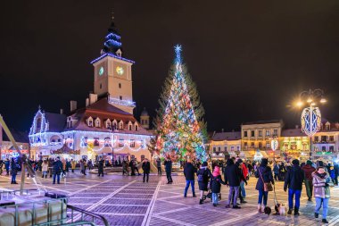 Kasaba meydanında büyük bir Noel ağacı parlıyor. İnsanlar etrafında toplanmış, neşeli atmosferin tadını çıkarıyorlar. 13 Aralık 2024 Brasov Romanya