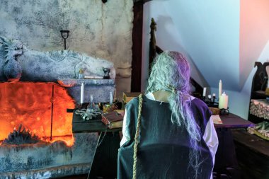 Uzun gri saçlı bir insan elinde mumla Drakula Kalesi 'nde oturuyor. 16 Aralık 2024 Bran Romanya.