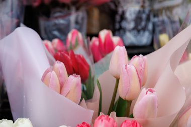 Pembe arka planı olan bir buket pembe ve beyaz çiçek. Çiçekler aynı yöne bakacak şekilde dizilmiş.