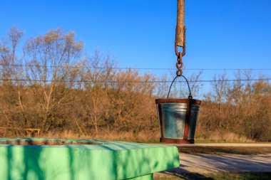 Zincirden bir kova sarkıyor. Kova mavi ve sapı var.