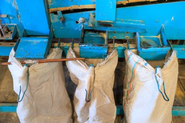 Üzerinde üç çanta asılı mavi bir makine. Çantalar beyaz, kırmızı ve yeşil çizgileri var.