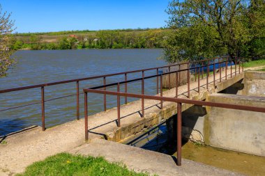 Berrak mavi gökyüzü ve yemyeşil yemyeşil göl üzerinde Rustik beton köprü.