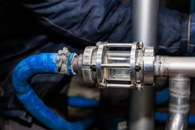 Mavi hortum ve metal valf bağlantıları olan endüstriyel boru hattına yakın plan..