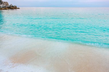 Okyanus sakin ve su mavinin güzel bir tonu. Kumsal kayalarla kaplı ve kum beyaz.
