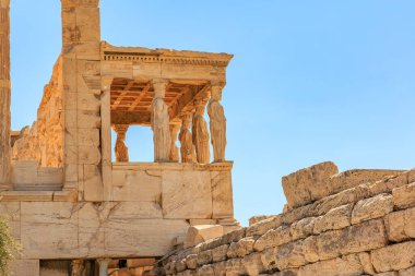 Üzerinde balkon ve birkaç heykel olan taş bir bina. Bina eski ve Atina 'daki Akropolis' te çok fazla tarihi var.