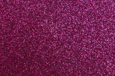 Pembe parlak bir yüzeye yakın çekim. Yüzey, yüzeyin her tarafına saçılmış küçük parıltı parçalarından oluşur. Parıltı çeşitli boyutlarda ve şekillerde.