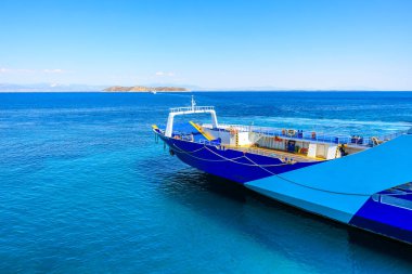 Mavi ve beyaz bir tekne okyanusa yanaştı. Su sakin ve gökyüzü berrak. 7 Ağustos 2024 Thassos 'tan Keramoti Yunanistan feribotu