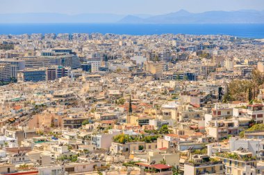 Arka planda büyük bir su kütlesi olan bir şehir manzarası. Şehir yüksek binalarla dolu ve bir sürü yeşil alanı var. 9 Ağustos 2024 Atina Yunanistan