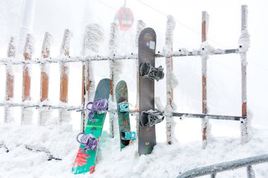 Sisli bir kış gününde kar kaplı snowboardlar ahşap çitlere yaslanıyor. 15 Aralık 2024 'te Romanya.