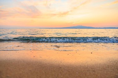 Okyanus sakin ve gökyüzü güzel turuncu bir renktir. Su gökyüzünü yansıtıyor. Huzurlu ve huzurlu bir atmosfer yaratıyor.