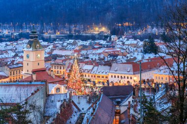 Ortasında Noel ağacı olan bir şehir. Ağaç ışıklarla çevrili ve insanlar etrafında toplanıyor.