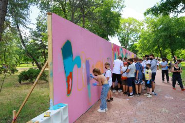 Çeşitli çocuk ve yetişkin grupları parka duvar yazısı çiziyor. 31 Mayıs 2024 Balti Moldova.