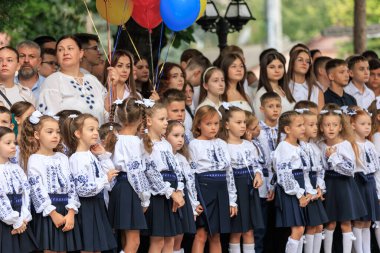 Bir grup beyaz çocuk ve yetişkin geleneksel giysiler içinde açık hava toplantısında. 2 Eylül 2024 Balti Moldova.