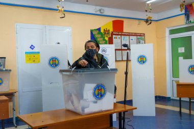 Kadın seçmen, seçim merkezinde güvenlik protokolleriyle oy kullanırken görülüyor. 21 Kasım 2021 Balti, Moldova.