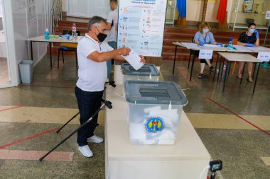 Seçimler sırasında sandık merkezinde güvenlik önlemleriyle oy veren yaşlı beyaz bir erkek. 11 Temmuz 2021 Beltsy, Moldova.