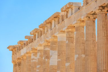 Sütunlar taştan yapılmıştır ve çok uzundur. Gökyüzü mavi ve berrak. Sütunlar çok eski ve Atina 'daki Akropolis' in uzun bir tarihi var.