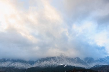 Bulutlu gökyüzü, alacakaranlıkta karla kaplı sıradağların üzerinde..