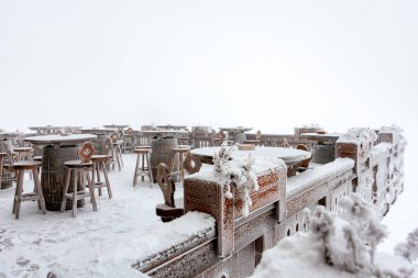 Kışın kırsal tabloları ve sandalyeleri olan karla kaplı açık yemek alanı..