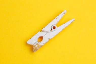 Parlak sarı arka planda tek aşınmış ahşap mandal..