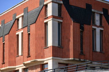 Benzersiz mimari tasarımı ve açılı çatısı olan modern tuğla bina.