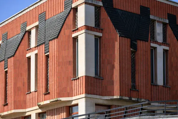 Benzersiz mimari tasarımı ve açılı çatısı olan modern tuğla bina.