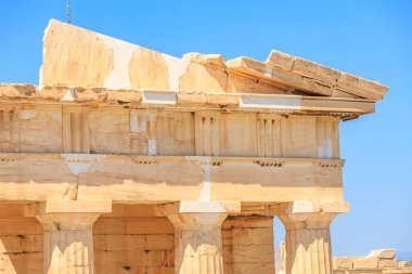 Binanın bir sürü beyaz ve kahverengi taşı var. Taş çok eski ve elementler tarafından aşınmış. Gökyüzü çok açık ve mavi, Atina 'da Akropolis